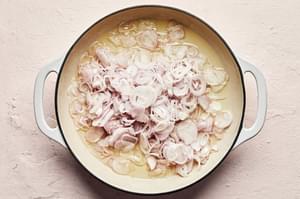 thinly sliced shallots being fried until crispy in a skillet with vegetable oil