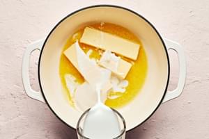 milk being poured over sticks of butter in a large pot