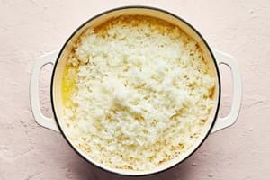 potatoes, butter, milk, salt and garlic powder being mashed together in a large pot