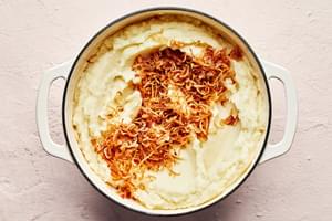 crispy shallots on top of creamy mashed potatoes in a large pot