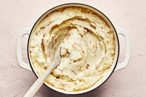 crispy fried shallot and creamy mashed potatoes being stirred together in a large pot