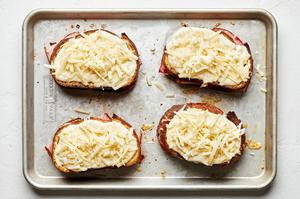 4 baked croque monsieur sandwiches topped with homemade béchamel sauce and Gruyère cheese ready to go back in the oven