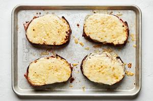 4 homemade croque monsieur sandwiches fresh out of the oven topped with béchamel sauce and melted cheese o a baking sheet