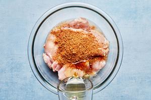 lime juice being poured into a large bowl with raw chicken thighs, olive oil and taco seasoning
