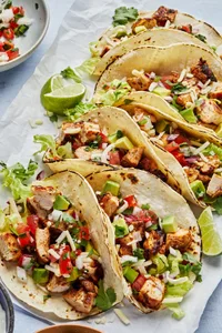 easy chicken tacos on corn tortillas topped with shredded cheese, lettuce, tomato and avocado