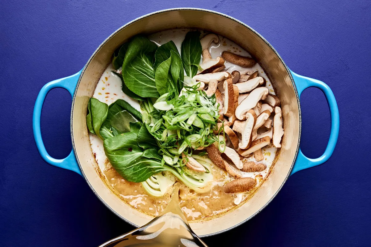 easy curry ramen being cooked in a pot with chicken stock, ground pork, mushrooms, and bok choy