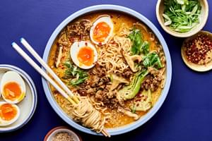 A pot of easy curry ramen with noodles, and vegetables submerged in a golden curry broth topped with soft boiled eggs