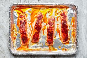 Four cooked salmon filets seasoned with curry paste, salt, brown sugar and garlic power on a foil lined baking sheet