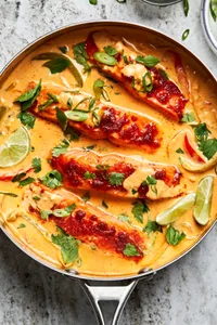 homemade curry salmon made with four filets of salmon in a coconut curry broth in a skillet topped with cilantro