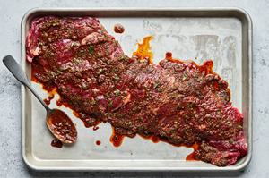 flank steak being marinaded in olive oil, lime juice, taco seasoning, soy sauce, and cilantro
