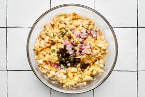 finely diced red onion and capers being mixed into to creamy egg salad sandwich filling