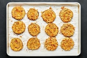12 crispy breaded baked eggplant slices arranged on a parchment lined baking sheet.