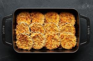 Crispy breaded eggplant arranged in a cast iron baking dish.