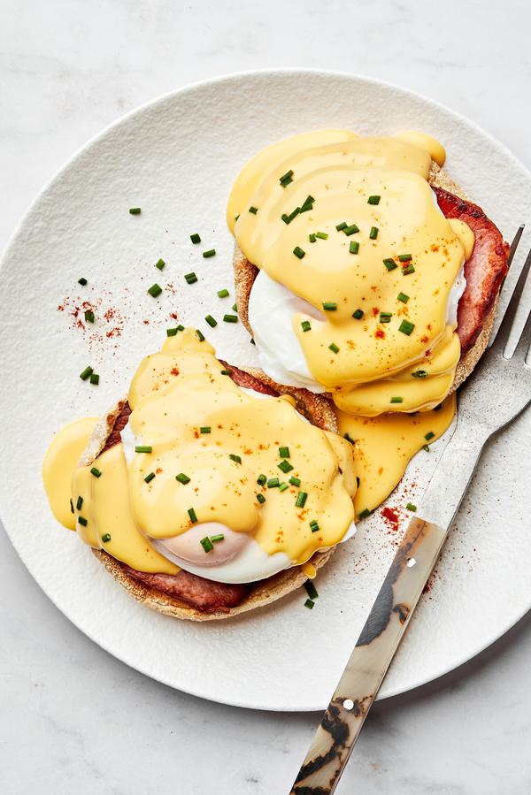 homemade eggs Benedict made with Canadian bacon and homemade hollandaise sauce on a plate with a fork