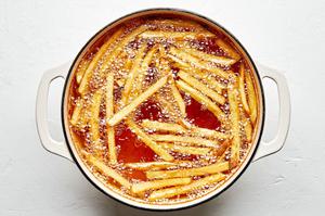 homemade French fries being fried in a pot of vegetable oil to use for fish and chips