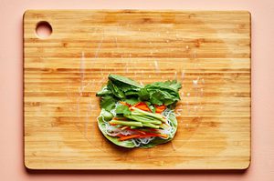 fresh spring rolls being assembled with lettuce, vermicelli noodles, vegetables and fresh herbs on rice paper