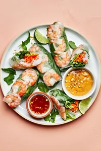 a plate of homemade fresh shrimp spring rolls served with creamy peanut sauce and sweet chili sauce for dipping