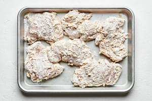chicken things dip din an egg mixture then dredged in flour, cayenne, salt pepper and garlic on a baking sheet