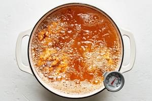 breaded chicken frying in a pot of vegetable oil for fried chicken sandwiches