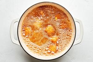 cheese cubes breaded with flour, salt, pepper, garlic powder, eggs and panko frying in a pot of vegetable oil
