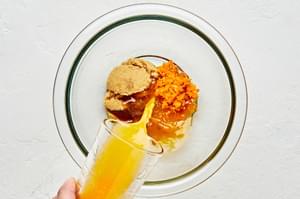 orange juice being poured into a bowl with orange zest, brown sugar and vanilla for orange dressing to go on fruit salad