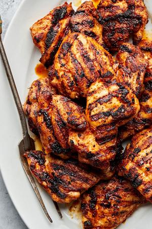 Grilled chicken thighs with beautiful grilled marks on a platter with a serving fork
