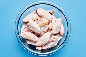 raw chicken wings in a glass mixing bowl