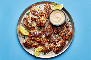 Grilled Lemon pepper chicken wings topped with parmesan and parsley, drizzled with lemon pepper sauce on a serving platter