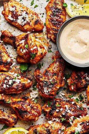 Grilled Lemon pepper chicken wings topped with parmesan, parsley and lemon pepper sauce with extra sauce beside for dipping