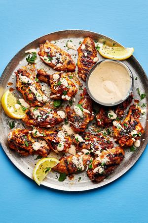 Grilled Lemon pepper chicken wings topped with parmesan and parsley, drizzled with lemon pepper sauce on a serving platter