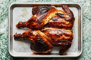 a whole spatchcocked grilled lemongrass chicken resting on a baking sheet