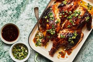 Grilled Lemongrass Chicken drizzled with sriracha-brown sugar sauce and scallion oil next to bowls of extra sauce & oil