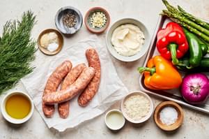 sausage, mixed vegetables, olive oil, dill, mayo, parmesan, garlic, lemon juice and spices in bowls on the counter