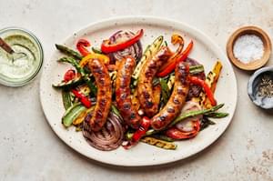 Grilled Sausage and Vegetables on a platter next to bowls of Creamy Dill Dip, salt and pepper