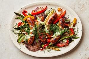 Grilled sausages and vegetables dried with creamy dill dip and sprinkled with fresh dill on a serving platter