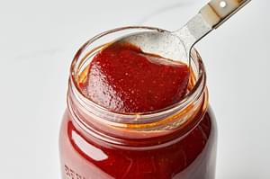 homemade bbq sauce being scooped out of a glass jar