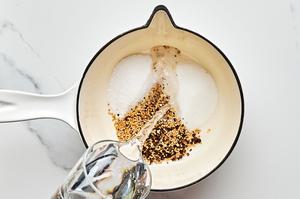water being poured into a sauce pan with crushed mustard seeds, peppercorns, vinegar, sugar and salt