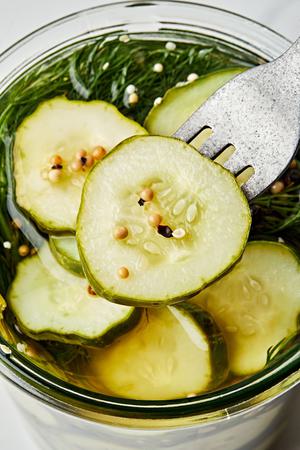 a fork scooping scooping a sliced pickled out of a jar of homemade dill pickles