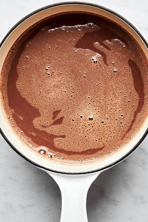 homemade hot chocolate in a small pot made with whole milk, sugar, cocoa powder, salt, vanilla and semi-sweet chocolate chips