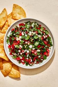 homemade pico de Gallo in a serving bowl surrounded by tortilla chips for serving