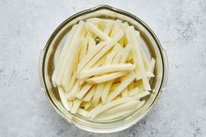 russet potatoes cut into fries soaking in cold water in a bowl