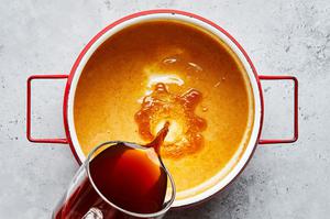 chicken and beef broth being poured into a saucepan with butter, flour, garlic and onion powders to make gravy for poutine