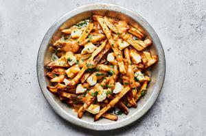 homemade poutine in a silver pie plate made with homemade fries topped with cheese curds and homemade gravy