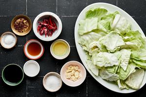 ingredients for homemade hot and sour cabbage in bowls on the counter including soy sauce, garlic and Sichuan peppercorns
