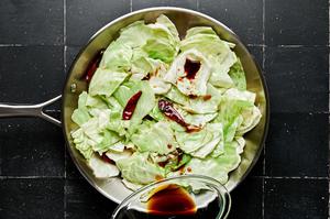 sauced being poured over cabbage in a skillet to make hot and sour cabbage