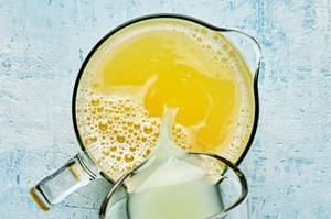fresh squeezed lime juice being poured into a pitcher of homemade pineapple aqua fresca made with water, pineapple and sugar