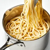pasta noodles that have been cooked in salted water being pulled out of a pot with tongs