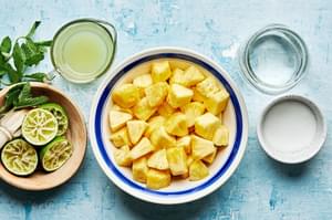 diced pineapple, lime juice, sugar, water and mint sprigs in bowls on the counter to make pineapple aqua Fresca