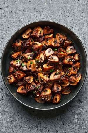 roasted cremini mushrooms seasoned with olive oil, salt, pepper, garlic cloves and fresh thyme in a serving bowl