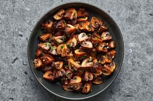 roasted cremini mushrooms seasoned with olive oil, salt, pepper, garlic cloves and fresh thyme in a serving bowl